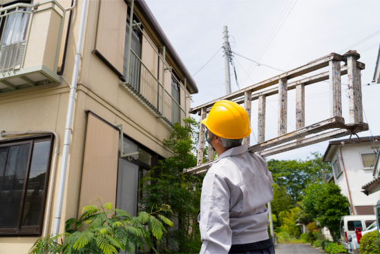 大型の脚立を運搬する作業員